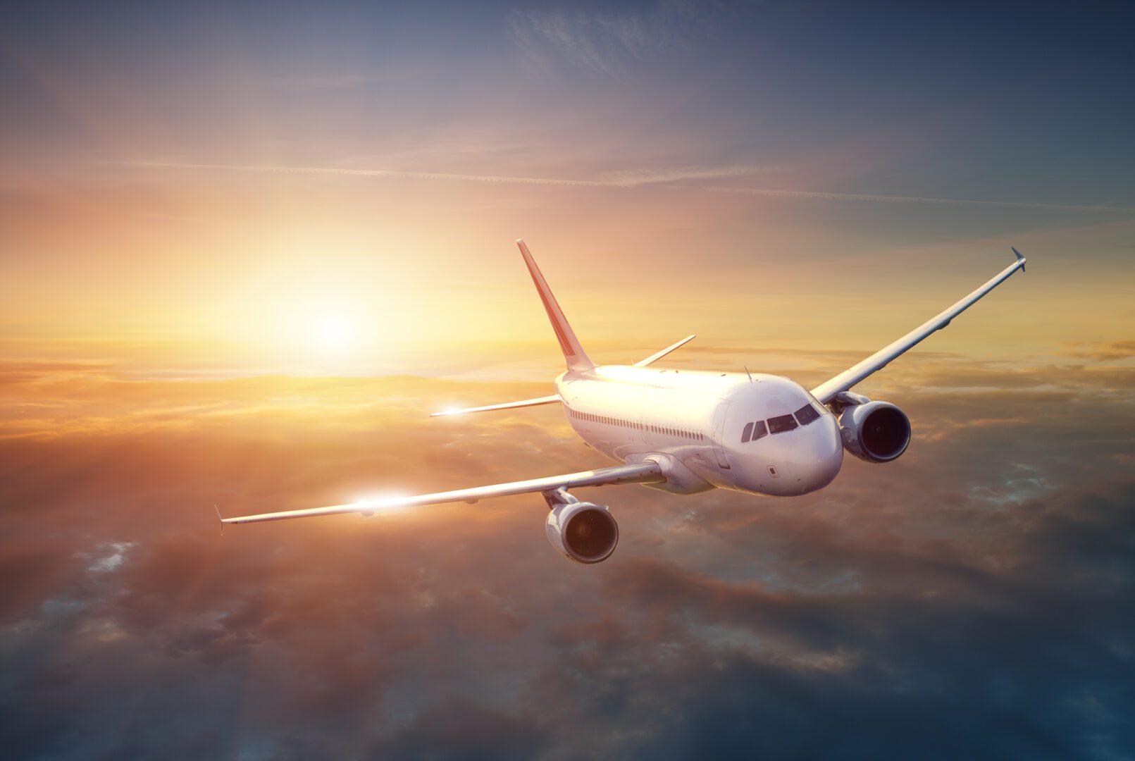 A plane flying in the sky at sunset.